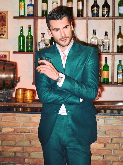 The green linen suit in a relaxed bar setting. It’s a versatile ensemble that transitions seamlessly from an afternoon event to an evening party.