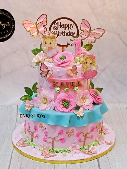 A beautiful two-tier cake with a fairy and butterfly theme. The pink and aquamarine hues are complemented by delicate sugarpaste flowers and fluttering butterflies for an ethereal look.