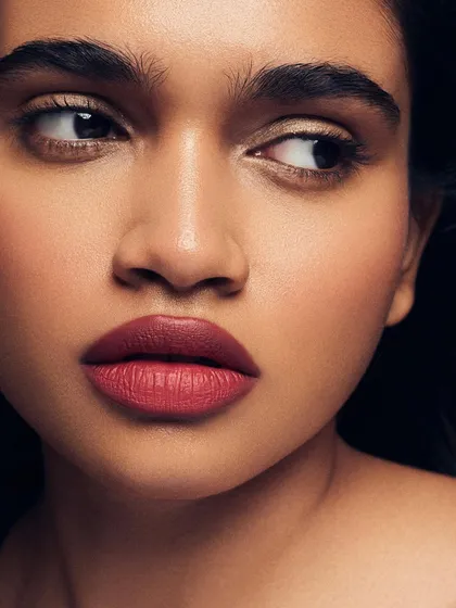 A close-up on a classic red lip glam. The focus is on the rich color and precise application of the lipstick, balanced by soft, natural skin and subtly defined eyes.