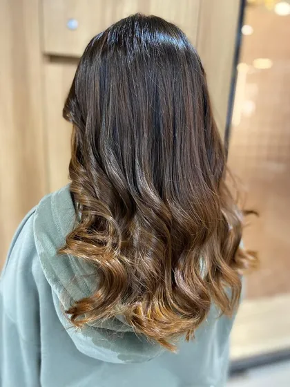 The final result of our color correction service. The hair is now a beautiful, multi-tonal brown with soft waves, looking healthy, vibrant, and completely revitalized.