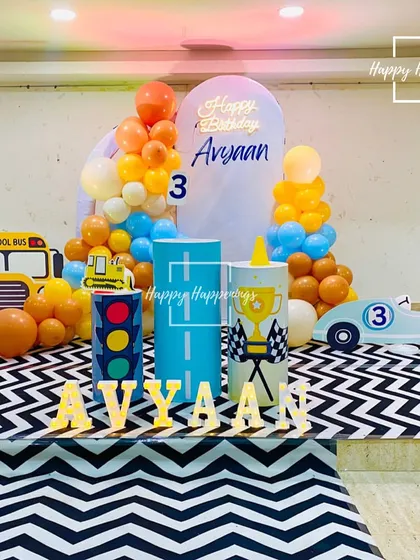 The complete car-themed setup for Avyaan's 3rd birthday. The arrangement includes a backdrop, themed plinths, marquee letters, and fun vehicle cutouts, all set against a chevron-patterned floor mat.