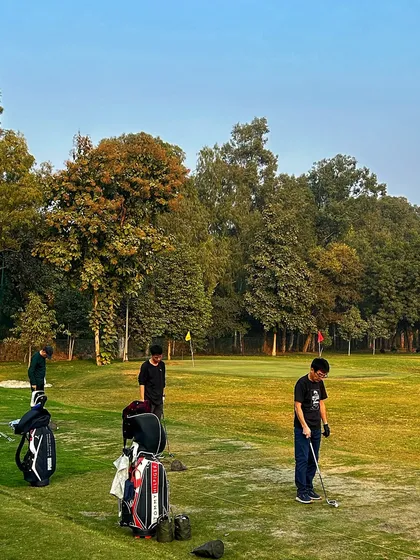 A group of friends practices on the grass tees, enjoying the golden hour light and good company.