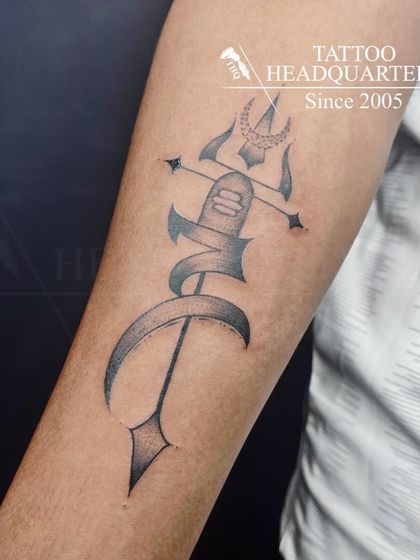 A custom tattoo design featuring a Trishul with the letter 'M' wrapped around it, personalizing a powerful spiritual symbol.