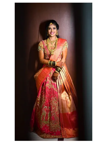 A full bridal look for a radiant client. I designed this traditional half-saree lehenga with a heavily embroidered pink blouse and a contrasting gold skirt, focusing on creating a timeless piece for her special day.
