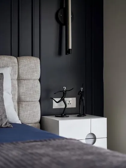 A detail shot of the guest bedroom, showing the contrast between the deep blue wall and the crisp white bedside table. The small, sculptural decor adds a personal touch.