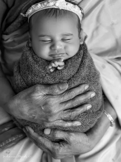 A powerful black and white portrait of a newborn being held by their great-grandmother. Four generations of love in one photo.