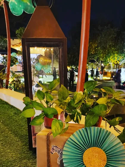 A detail shot of the outdoor decor, featuring a lantern with greenery and a themed paper fan. These small touches help carry the safari theme throughout the event space.