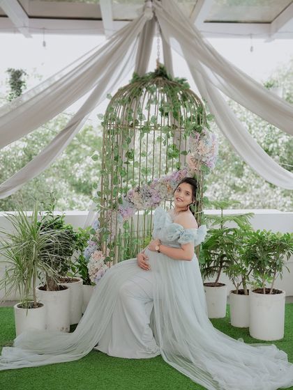 A serene moment captured in our light blue Isabella gown. The long, flowing trail and off-shoulder ruffles create a soft and elegant silhouette, perfect for outdoor garden shoots.