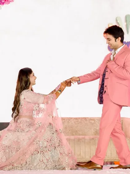 A playful and romantic moment on the engagement stage. The groom leads his bride in a dance, their smiles reflecting the joy of the celebration, framed by a magnificent floral arch.