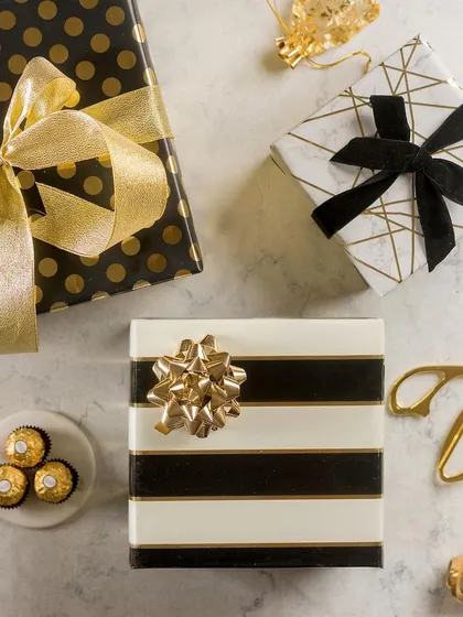 A chic and sophisticated flat lay of gifts wrapped in black, white, and gold paper. Paired with Ferrero Rocher chocolates, this image creates a sense of luxury and indulgence.