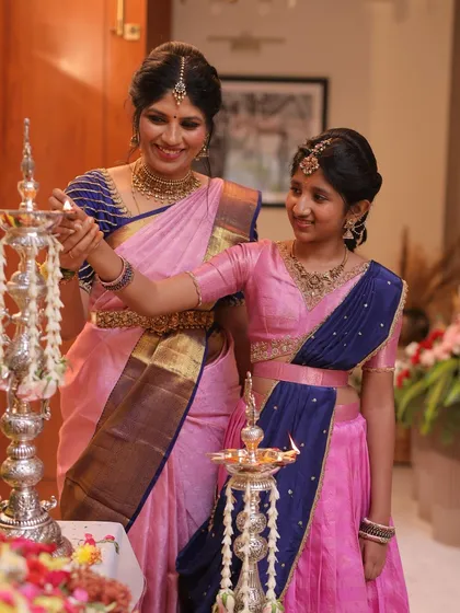 There's nothing more special than creating matching outfits for a mother and daughter. Seeing them share a moment like this, lighting a lamp together in coordinated pink and blue traditional wear, is the reason I pour my heart into every piece.