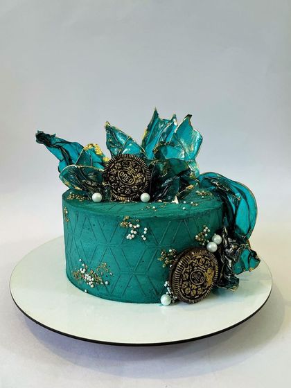 Here is the same modern design concept executed in a vibrant jade green. The contrast with the gold-dusted Oreos and dark chocolate sails makes for a truly unique and artistic cake.