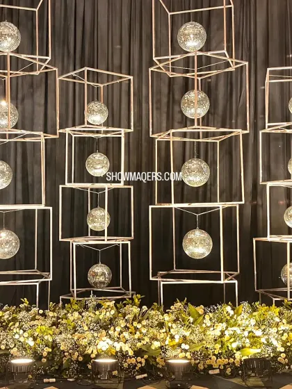 A modern art installation featuring suspended disco balls in geometric frames, serving as a unique decor element for a cocktail party.