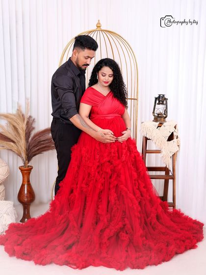 A romantic couple's portrait in our bohemian studio setup, with the mother-to-be in a red ruffled gown.