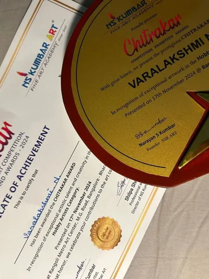 A proud moment for our student Varalakshmi N, receiving her Chitrakar Award certificate and trophy. We celebrate every student's contribution to the art community.