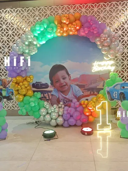 A fun Disney Cars themed first birthday with a circular balloon arch and cutouts of Lightning McQueen and Mater.