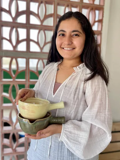 Mansa holding two of her handled bowls, showing the beautiful glaze variations.