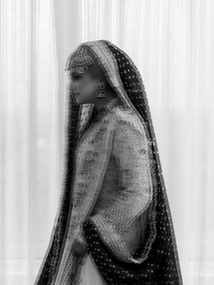A classic black and white side profile of a Muslim bride. The focus on the intricate details of her dupatta and her graceful posture creates a timeless and artistic portrait.