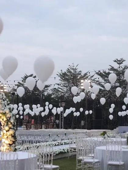 A sky full of white balloons adds a touch of whimsical magic to this dreamy white wedding setup.