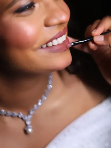 A close-up action shot of me applying lipstick. This highlights the precision and care I take to ensure every detail of the bridal makeup is perfect.