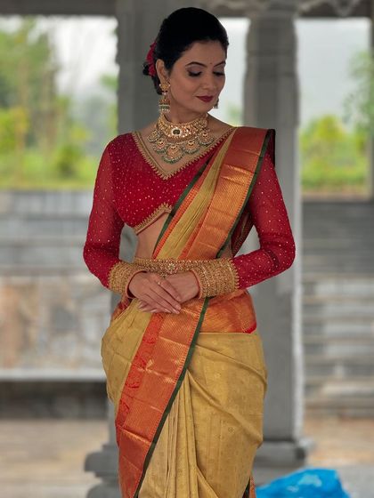 A full-length view of the red and gold Kanchivaram look, showing the beautiful drape of the saree and the striking contrast of the embroidered red net blouse.