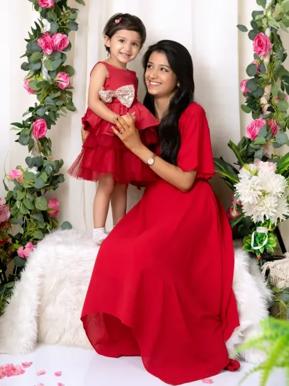 A mother and her little girl in a matching red dress share a smile during their special photoshoot in the studio.