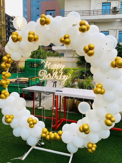 An elegant white and gold balloon ring set up for an outdoor home party, perfect for a garden or backyard.