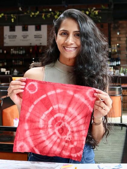 The same participant, beaming with pride over her handcrafted tie-dye creation. Workshops like these are about learning a skill and experiencing the joy of making.