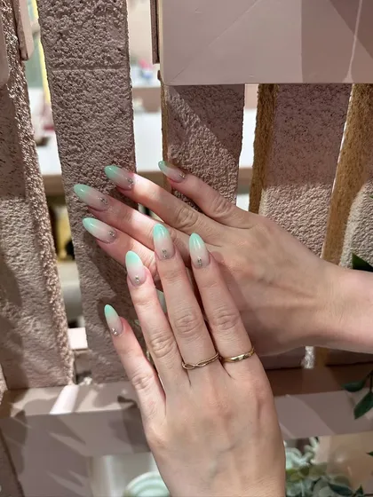 The almond shape of the nails perfectly complements the soft fade of this mint green ombré design.