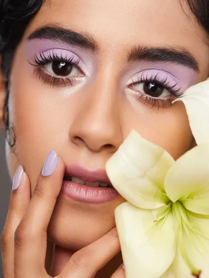 A soft and dreamy look with pastel lavender eyeshadow, paired with a matching manicure and a beautiful white flower.