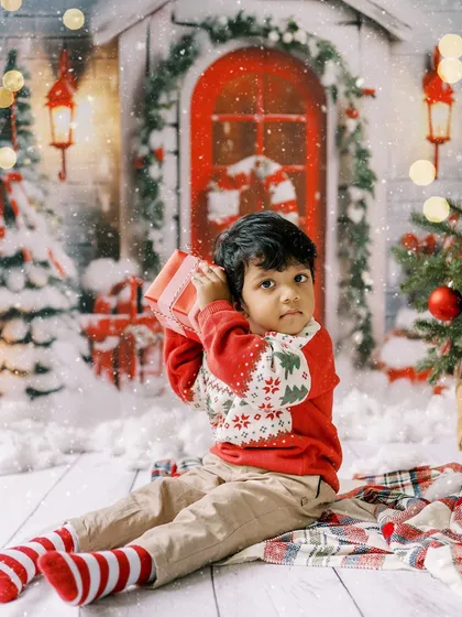 A little boy checking his gift, sitting amidst a snowy Christmas scene. The wonder in his eyes is what the holidays are all about.
