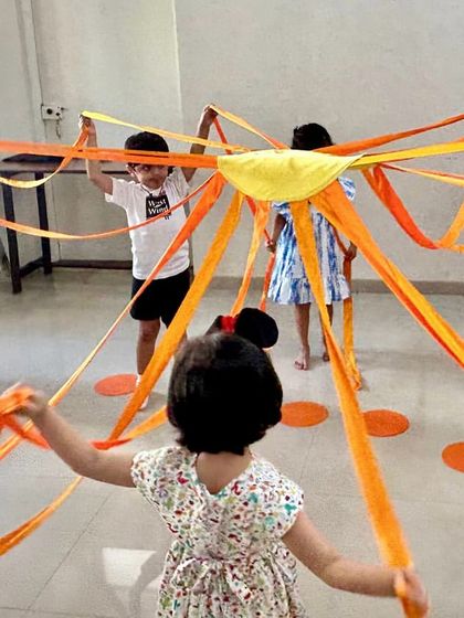 A group of children works together with a sun prop, learning about teamwork and musical form through a guided activity.