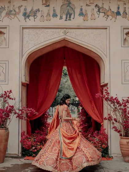 The bride looking ethereal against a backdrop of heritage architecture and dramatic red drapes.