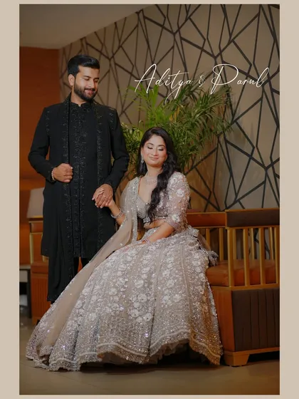 A lovely portrait of the engaged couple, with the bride seated and the groom standing beside her, holding her hand.