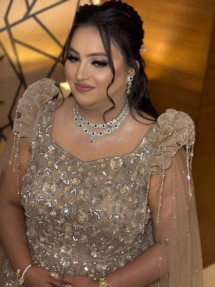 A beautiful portrait of the client, looking radiant and confident. The updo hairstyle and statement jewelry complete her elegant evening look.