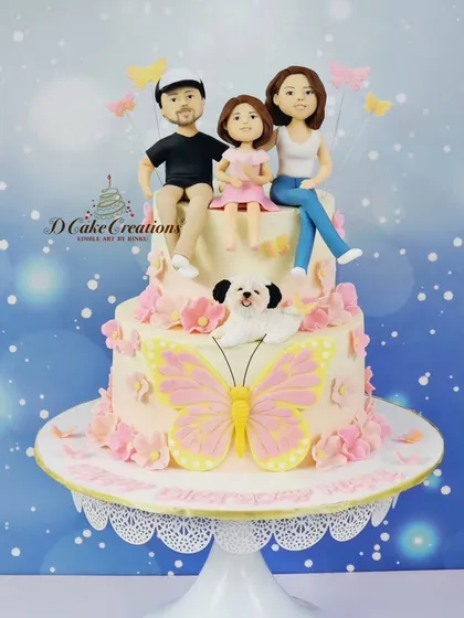 A full view of the two-tier family cake for Soha Ali Khan. It features edible figurines of the family, their dog, and is decorated with delicate sugar flowers and butterflies.