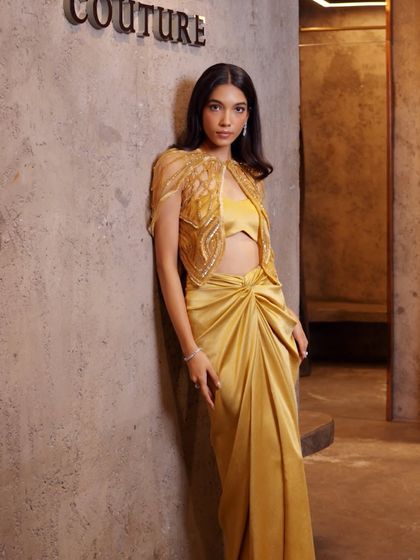 Grace in every drape, elegance in every detail. This mustard-hued vision features a draped skirt, an intricately embroidered blouse, and a cutwork cape that adds the right touch of drama.