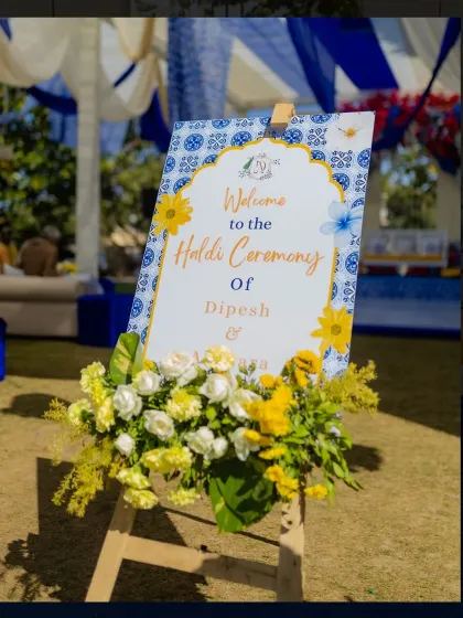 A close-up of the elegant welcome signage for the Haldi ceremony, framed with fresh yellow and white flowers.