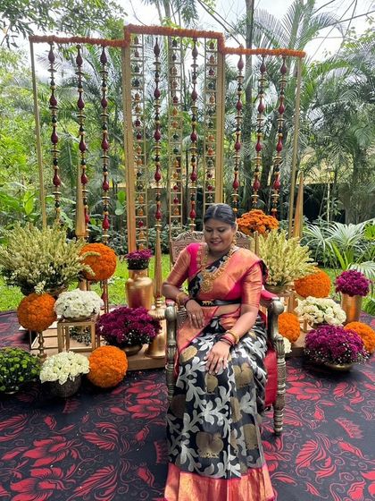 Pavithra seated in a beautifully decorated outdoor setting, her saree a perfect fit for the festive occasion.
