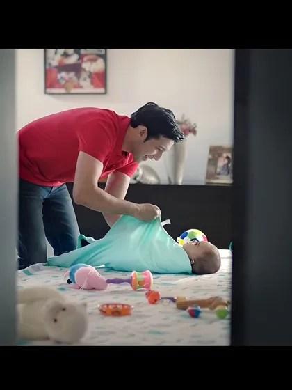 Another shot from the baby care campaign, showing me swaddling the baby. These scenes are designed to be authentic and emotionally resonant for parents watching the ad.