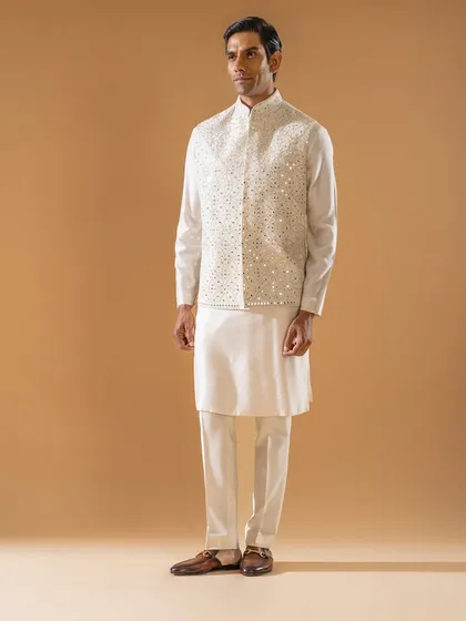 An expression of pure, understated luxury. This classic ivory-on-ivory ensemble features a Jawahar jacket intricately embellished with mirror work, offering a look of serene elegance that is both traditional and effortlessly stylish.