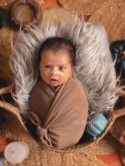 Sometimes the awake moments are just as precious. This alert newborn looks directly at the camera while swaddled in a basket, surrounded by cozy, rustic props.