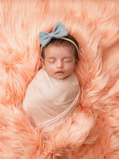 A full view of the newborn swaddled on a fluffy peach blanket. This simple setup is all about comfort, color, and cuteness.
