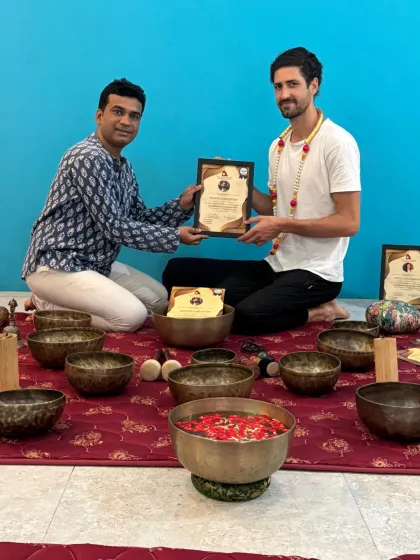 A graduate of our Sound Healing TTC is congratulated as he receives his certificate.