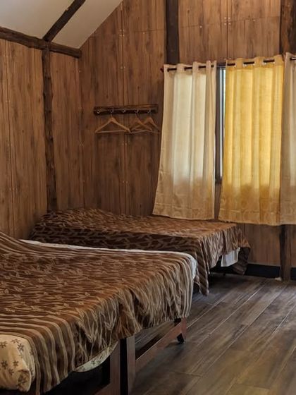 The simple and clean interior of a wooden cottage at the Dandeli camp, providing a comfortable place to rest after your adventures.