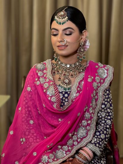 A portrait of bridal elegance. The sleek updo ensures that every detail of her jewellery, from the nath to the maang tikka, is highlighted, creating a polished and sophisticated look for her wedding ceremony.