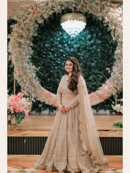 A beautiful portrait of the bride standing before a circular floral arch. The grand decor and her graceful pose create a picture-perfect image of bridal elegance.