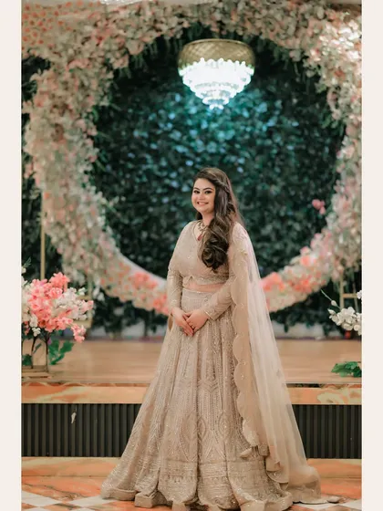 A classic portrait of Ishita standing before a large floral ring, her smile lighting up the frame.