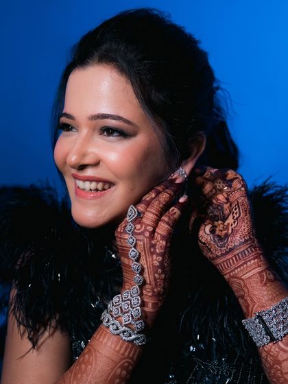 A beautiful shot of the bride adjusting her earring, showcasing her sparkling diamond jewelry and detailed henna. We capture the elegance in every detail.