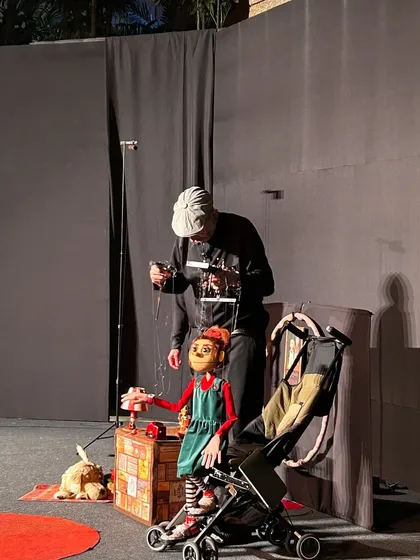 The puppeteer adjusts the strings of the main character from 'Pay Attention to Those Two'. The intricate controls allow for a wide range of movement and expression.